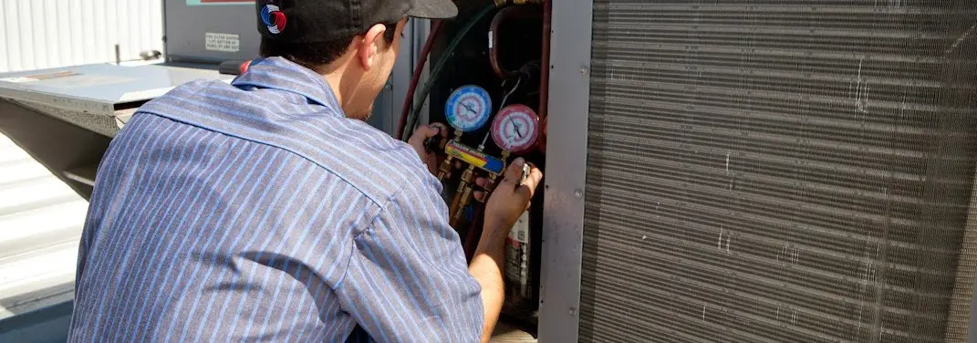HVAC technician servicing a condenser unit in Egg Harbor